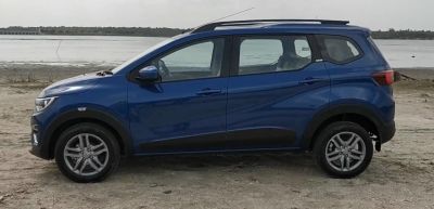Side profile of a compact multi-purpose vehicle with roof rails and alloy wheels.