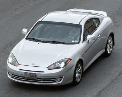 Sports coupe front view with sleek headlights and alloy wheels