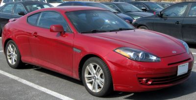 Red two-door sporty coupe with prominent front headlights and alloy wheels
