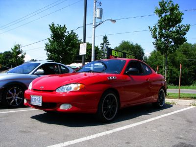 Red coupe with black alloy wheels and sporty side vents