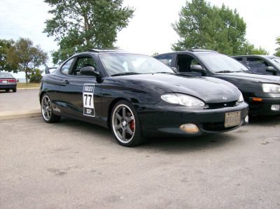 Front-side view of a black coupe with racing decal and sporty wheels