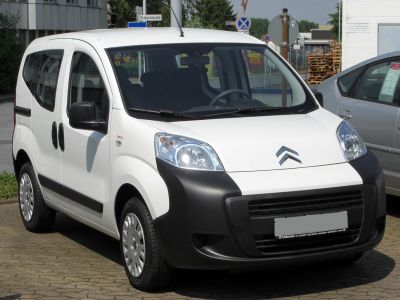 Compact van front view with high roof, sliding doors, and large black bumper.