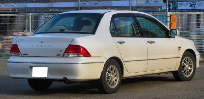 White sedan rear-side view with alloy wheels and clear red taillights