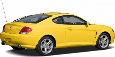 Rear side view of a yellow coupe with alloy wheels and rear spoiler