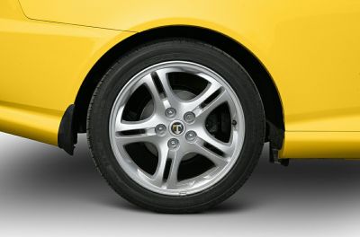 Close-up of silver alloy wheel with tire on yellow sports coupe.