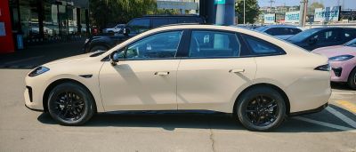 Electric sedan side profile with black alloy wheels.