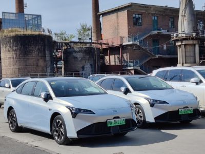 Two white electric sedans front and side view in urban parking.