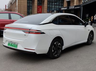 Rear and side profile of a sleek white electric sedan with distinctive taillights.