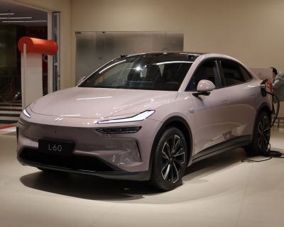 Electric sedan with sleek front design and charger plugged in