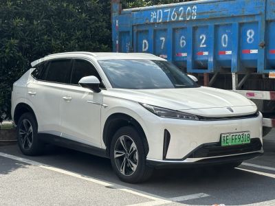 Front-side view of a sleek white electric SUV with LED headlights.