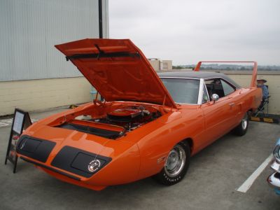 Orange muscle car with open hood exposing engine and large rear wing