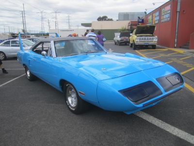 Bright blue classic muscle car with large rear wing and aerodynamic nose.