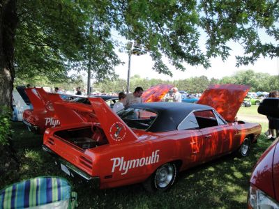 Bright orange classic muscle car with large rear wing and vinyl roof.