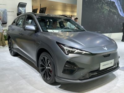 Front side view of matte gray electric crossover with sharp LED headlights and black alloy wheels