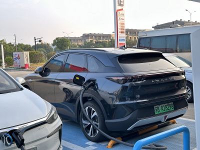Black electric SUV charging at public EV station with modern design
