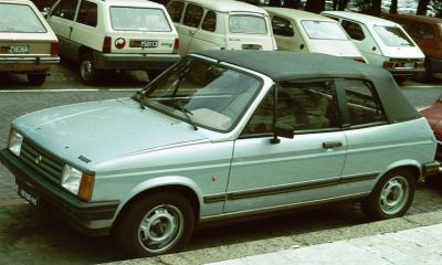 Small vintage convertible with black soft top and compact design.