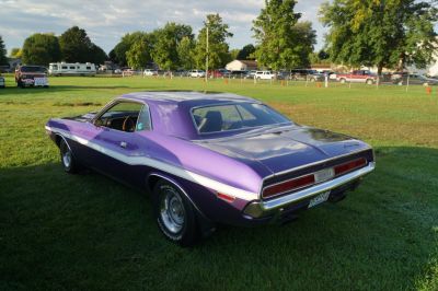 Rear side view of a purple vintage muscle car with sleek contours and retro design.