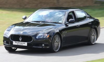 Luxury sedan in motion with prominent grille and sporty alloy wheels