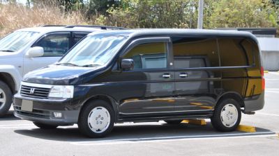 Black minivan with sliding doors and compact design, side profile view