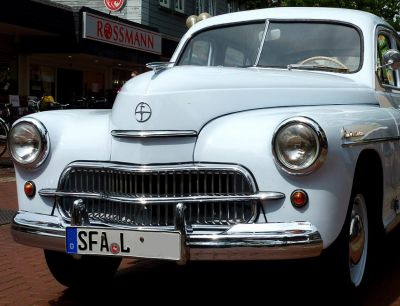 Close-up of vintage car front grille and round headlights with chrome details.