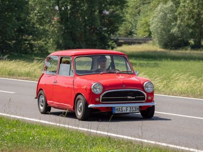 Classic vintage red compact car with round headlights and chrome bumper