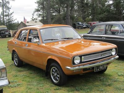 Front three-quarter view of classic vintage sedan with distinctive orange paint