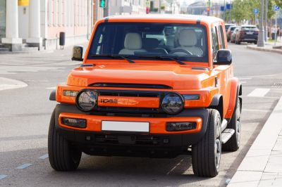 Front view of orange SUV with round headlamps and rugged design