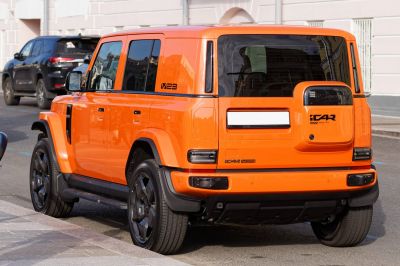 Boxy orange SUV rear and side view with black rims and modern design