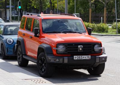 Orange SUV with round headlights, roof rails, and black fender flares