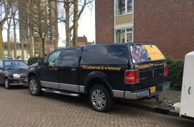 Black extended pickup truck with promotional graphics and towing hitch