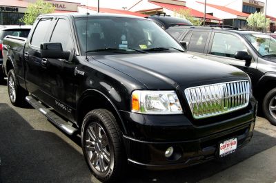 Front and side profile of a black pickup with chrome grille and alloy wheels