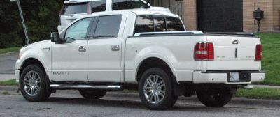 White luxury pickup with crew cab, chrome wheels, and covered cargo bed