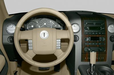 Beige leather steering wheel and wooden dashboard trim with controls