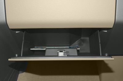 Open glove compartment with beige and black interior showing storage space and documents.