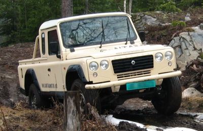Off-road rugged 4x4 pick-up truck navigating muddy forest terrain
