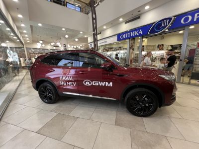 Side profile of a red SUV with black alloy wheels and hybrid model decals