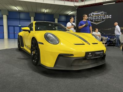 Low-angle front view of a yellow sports coupe with black racing stripes and rims
