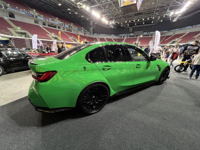 Green sport sedan with black wheels and rear spoiler