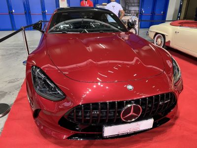 Close-up of sleek front grille and LED headlights on a deep red sports coupe.