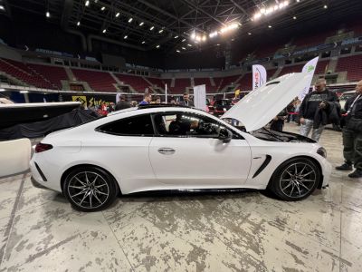 White two-door coupe with open hood and sporty alloy wheels