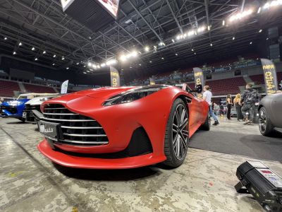 Low angle front and side view of a sleek red sports coupe with modern headlights and aggressive grille