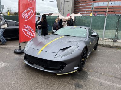Front view of sleek sports car with yellow racing stripe on matte grey surface