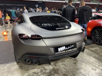 Rear view of a matte silver luxury coupe with dual exhaust and tinted taillights