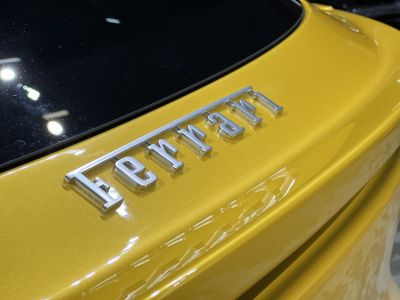 Close-up of silver Ferrari badge on yellow rear panel