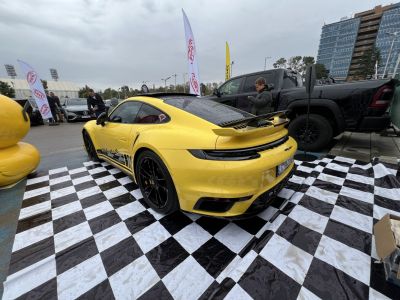 Yellow sports car with rear spoiler and black wheels on checkered floor