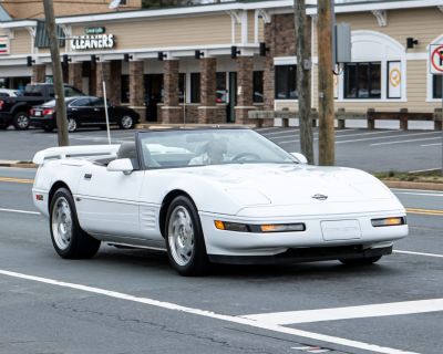 White convertible sports car with pop-up headlights and aerodynamic design