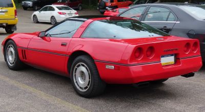 Rear side view of a red classic sports coupe with quad round tail lights and unique wheels.