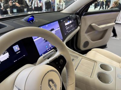 Beige leather steering wheel with digital dashboard and touchscreen.