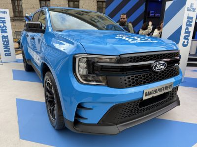 Front of blue electric pickup with modern headlights and honeycomb grille