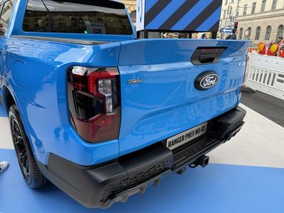 Rear tailgate and taillight of blue pickup with hybrid badge